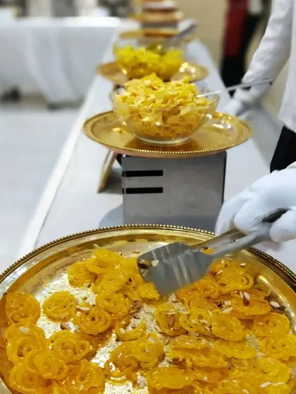Freshly made jalebis being served on a traditional brass platter. This is a very popular live dessert station at weddings and festive celebrations.