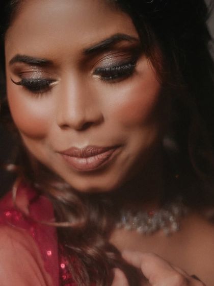 A moody and dramatic portrait. The lighting highlights the shimmer on her eyelids and the flawless texture of her skin.