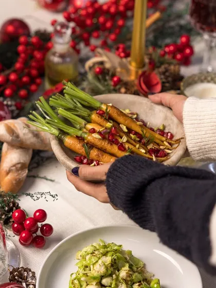Sharing is at the heart of every celebration. A dish of honey-glazed carrots with pomegranate seeds is passed around the table, part of our communal Holiday Feast.