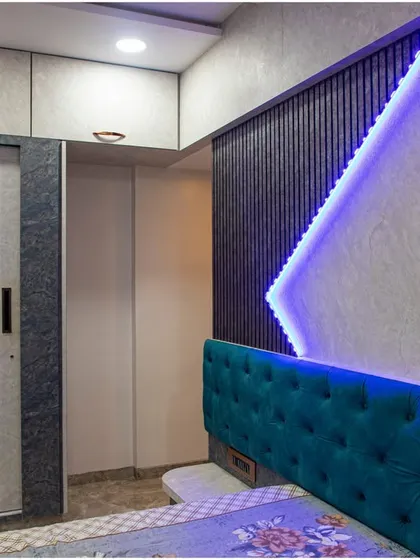 A bedroom design featuring a tufted teal headboard and a striking accent wall with geometric patterns and cool-toned LED lighting.