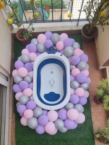 A creative baby shower prop featuring a baby bathtub surrounded by a wreath of pastel balloons.