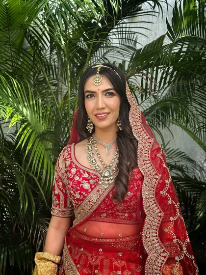 A beautiful portrait of the bride in her red lehenga, her makeup looking soft and flawless, with a focus on her radiant skin.