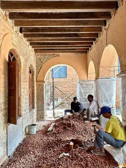 Workers clearing rubble from the restored arched corridor. This phase marks a transition from repair to finishing, as the final form of the space begins to emerge.