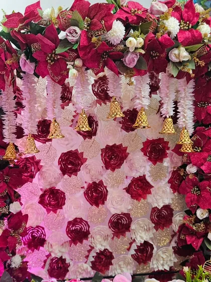 This intricate Navratri backdrop is made of red and pink flowers, with a lattice of hanging bells that adds a traditional and musical element. It's a rich and detailed design, perfect for welcoming the Goddess.