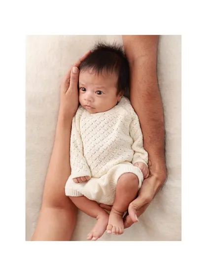 A newborn cradled safely in their father's arms. This perspective emphasizes how small and precious they are in these first few weeks.