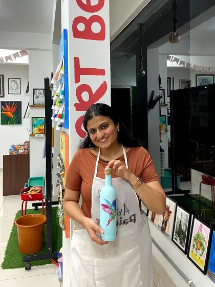 A student showcasing the beautiful bottle she decorated in a decoupage workshop. This is a great example of how we upcycle everyday objects into unique pieces of art.