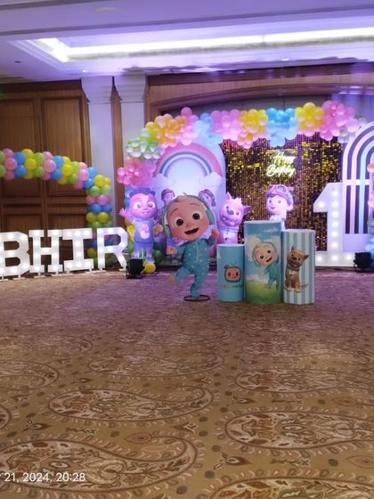 A wide view of the Cocomelon stage setup in a large banquet hall, showing the full scale of the decoration.