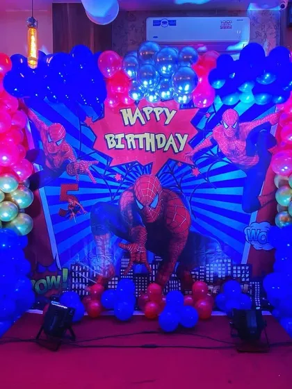 The main stage for a Spiderman party, complete with a city-scape backdrop, character cutouts, and dramatic balloon arrangements.