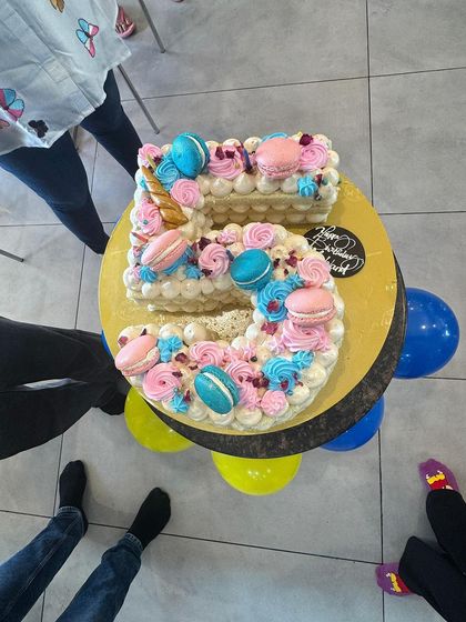 A closer look at the intricate details of a custom 5th birthday cake. Topped with pink and blue macarons and a golden unicorn horn, it's a perfect example of the beautiful treats I can provide for your party.