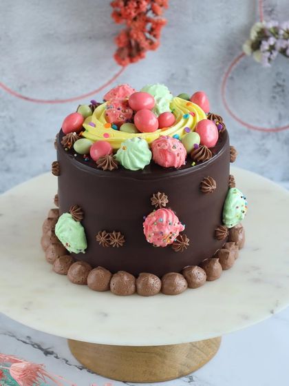 A rich chocolate ganache Easter cake, topped with colorful meringues and sprinkles. A truly indulgent festive treat.