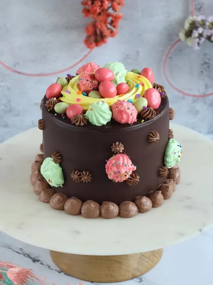A special Easter mini cake, decorated with colorful meringues and candy eggs. It's a rich chocolate cake perfect for a small family celebration.