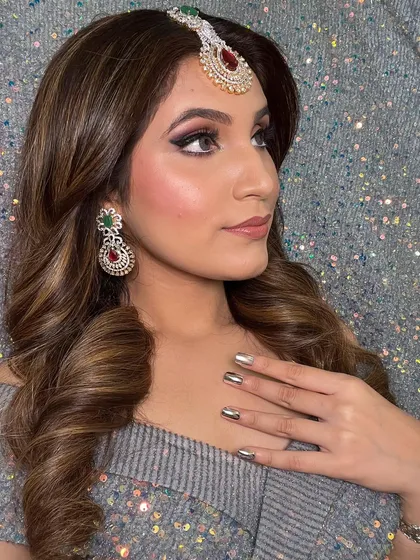 A side profile showing the soft curls and the way they fall. The metallic nails and statement jewelry complete this high-glam party look.