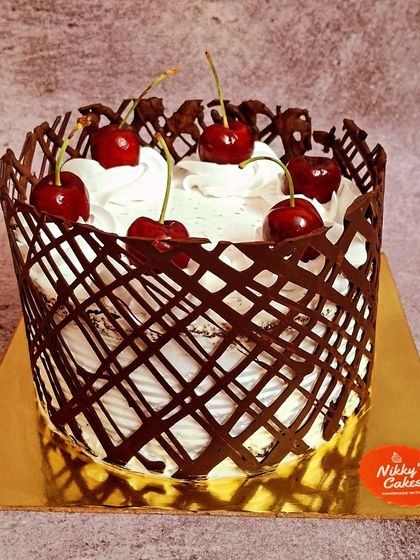 This is my take on the classic Black Forest cake. It features layers of chocolate sponge, fresh cream, and cherries, all enclosed in a beautiful, handcrafted chocolate lattice cage and topped with more fresh cherries.