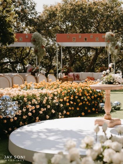 A wider view of the unique wedding stage, where a circular platform is surrounded by a dense garden of roses, leading to a modern, chic lounge area for guests.