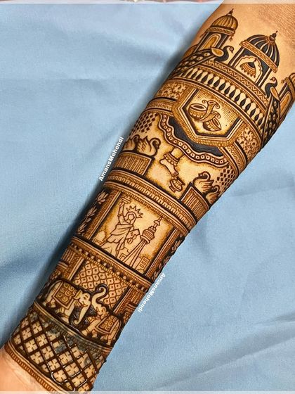 A beautiful bridal arm design combining traditional Indian motifs with global landmarks. This section features the Statue of Liberty and the CN Tower, representing the couple's story.