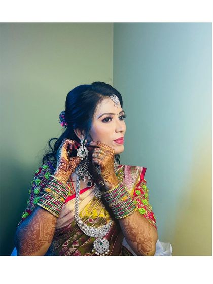Another angle of the bride adjusting her earrings. The side profile shows off the elegant hairstyle and the contouring that defines her features.