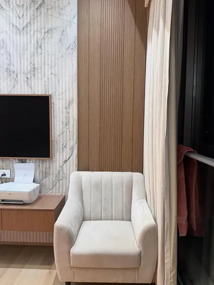 A comfortable reading corner next to the window in the master bedroom, featuring a plush armchair. It’s a perfect spot to relax and enjoy the city view.