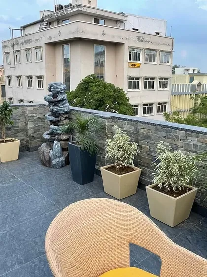 This rooftop seating area in Ashok Vihar is enhanced with a variety of potted plants and a small water feature. The combination of greenery and the sound of water creates a relaxing urban escape.