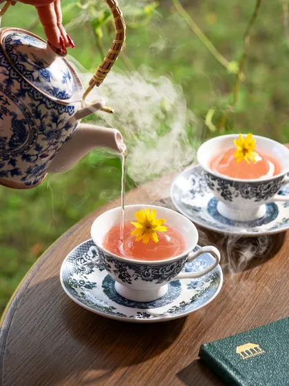 The gentle pour of steaming hot water into a delicate teacup, creating a sense of calm and ritual.