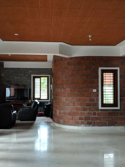 An open living space with a curved brick wall, marble flooring, and large glass doors, showing how natural materials can be used in a sleek, modern way.