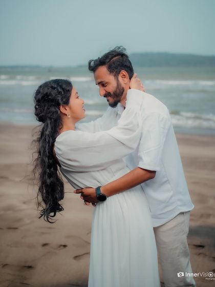 The couple shares an intimate dance-like embrace on the sand. The natural, candid feel of this photo highlights their comfortable and loving relationship.