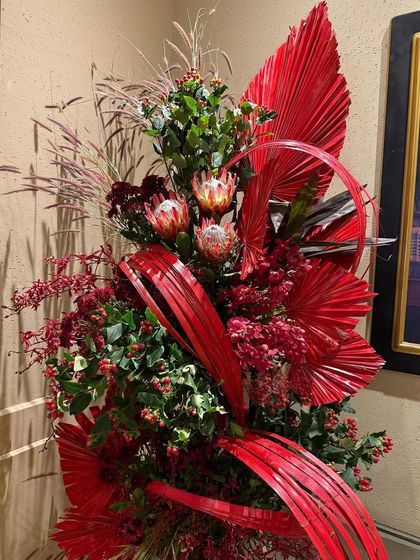 Detail of the Christmas decor, where sculptural red leaves and protea flowers create a focal point. I love playing with form and structure to give my arrangements a strong, artistic presence.