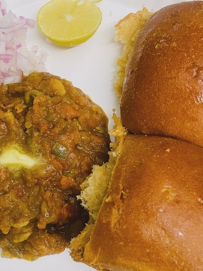 A close-up of our buttery Pav Bhaji. You can see the rich texture of the mashed vegetable curry topped with a dollop of butter, served with soft pav.