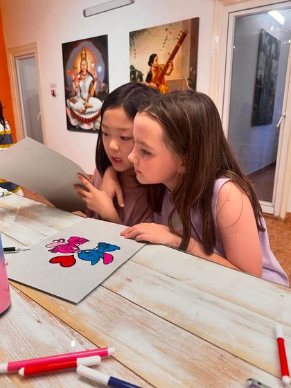 A moment of shared discovery as two students review their artwork together, discussing their progress and ideas.