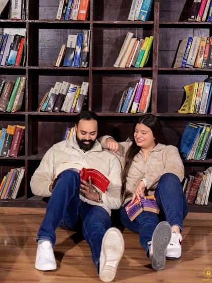 A relaxed photo of a couple sitting on the floor of our library set, engrossed in books. This setup is perfect for book-loving couples who want a cozy and personal pre-wedding shoot.