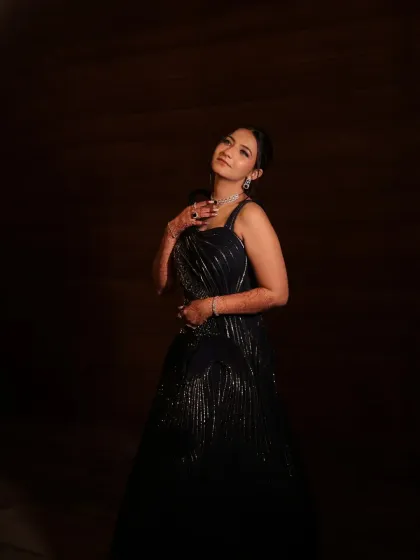 A dramatic, moody portrait for a Sangeet night. The bride's elegant black gown and glowing makeup create a look of pure sophistication.