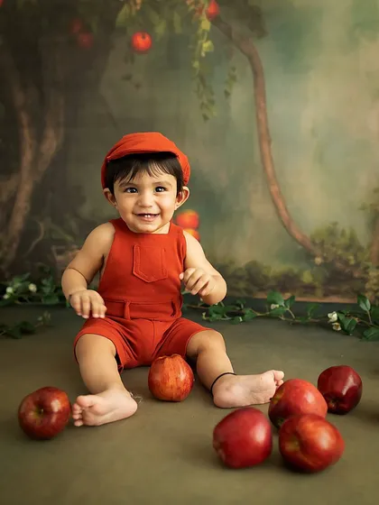 Another joyful shot from the 8-month apple-themed session, showing a happy baby ready to play.