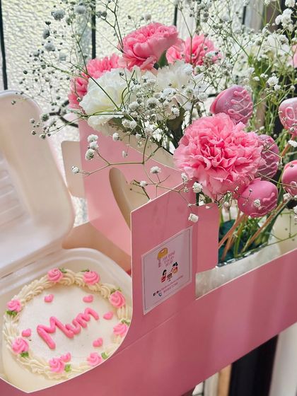 Another angle of our popular Mother's Day hamper. This view highlights the 'Mum' bento cake and the bouquet of pink carnations and glittery cake pops.