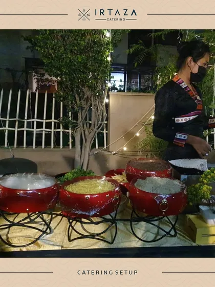 A simple yet elegant catering setup with red ceramic bowls, perfect for a more casual or themed event. The staff member in the background ensures everything is perfectly in its place.