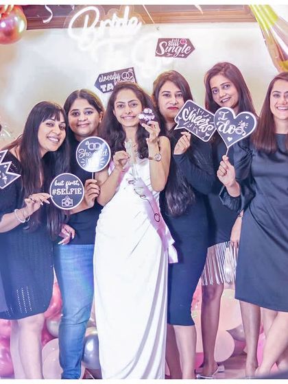 A happy bride tribe makes a happy bride! The whole group poses with fun props in front of our bridal shower balloon decor, capturing a moment of friendship and celebration.