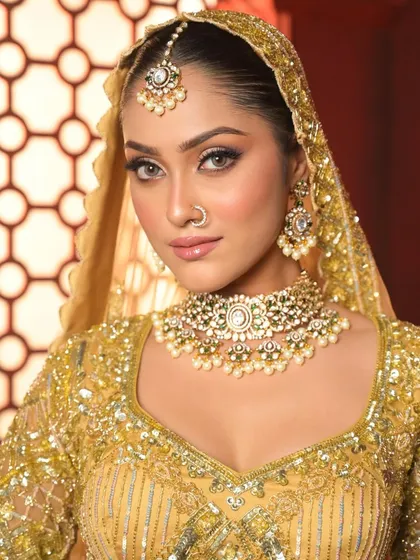 A close-up of the golden bridal look, highlighting the flawless skin, shimmering eyeshadow, and the intricate details of the jewelry.