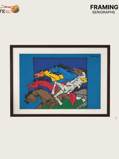 A colorful M.F. Husain serigraph depicting a flurry of horses. The dark wood frame provides a grounding contrast to the vibrant blues, reds, and yellows, making the colors appear even more vivid.