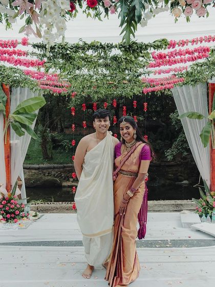 A lovely couple stands before a floral mandap, with the tranquil pond in the background. This shot captures the essence of a traditional South Indian wedding ceremony.