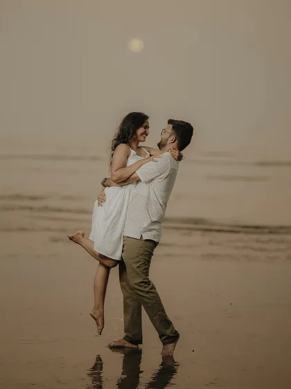 A joyful lift against the setting sun. This classic pre-wedding beach pose is full of happiness and romance, a perfect memory of their time by the sea.