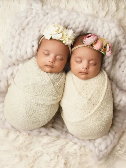 Swaddled side-by-side on a fluffy white blanket, these twin girls look like two perfect, tiny bundles. This is a classic and timeless twin newborn portrait.