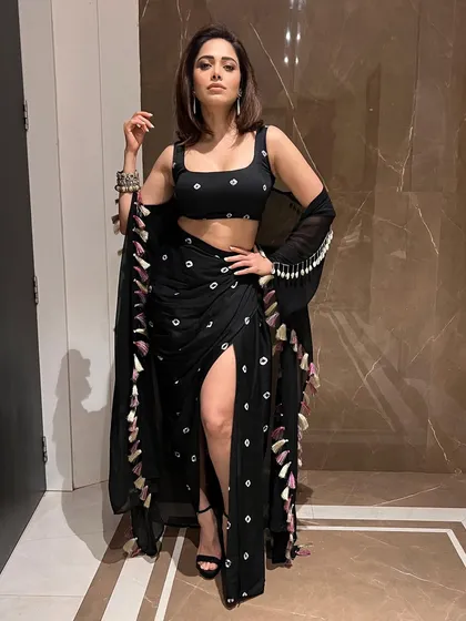 Here’s a boho-chic look I put together for Nushrratt Bharuccha. This black draped outfit with a thigh-high slit and tassel details is a great example of fusion wear that is both edgy and glamorous, perfect for a stylish evening event.