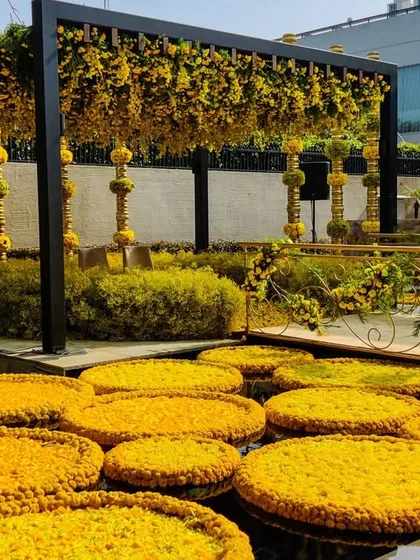 Floating discs of yellow marigolds in the water body at the residence, tying the entire space into the sunshine theme. The golden pillars in the background add a touch of traditional elegance.