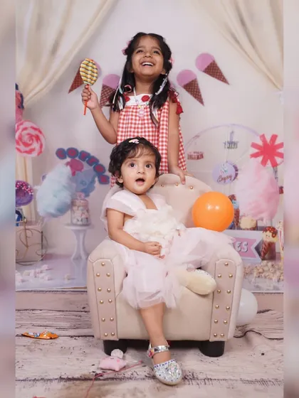 A fun moment between two sisters in the Candy Land set. The setup includes props like a giant lollipop, creating opportunities for interactive and playful photos.