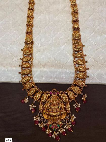 This 92.5 silver gold-plated necklace features a beautiful mango and peacock design. The large central pendant has a Goddess Lakshmi motif, making it a perfect piece of temple jewelry.