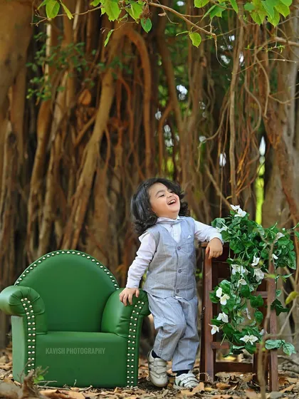A heartwarming outdoor portrait of a little boy laughing, dressed in a smart vest and suit.
