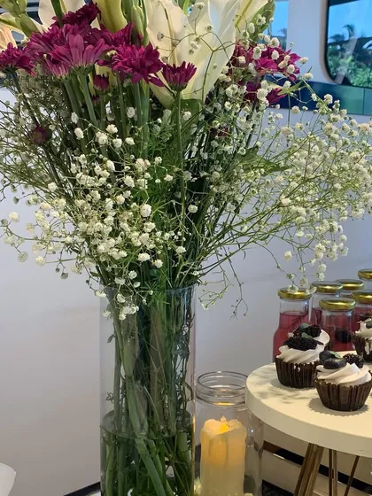 Another view of the fresh floral centerpiece, showing how it complements the dessert table. The details, like the candle and cupcakes, are all part of the overall event design.