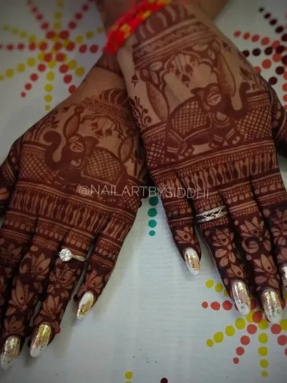 A stunning set of gold chrome nails that create a bold and luxurious statement, perfect for a bride who wants to shine. The metallic finish stands out beautifully against the detailed mehndi.