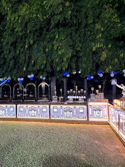 An evening party setup on a lawn, with our illuminated buffet counter standing against a backdrop of trees. The blue and white balloons indicate a birthday or celebratory gathering.