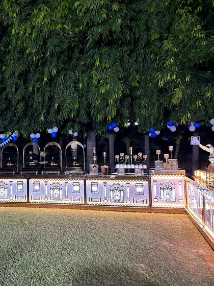 An expansive view of our beautifully lit catering counter at an outdoor evening event. The intricate design on the counter facade, combined with the lush green backdrop, creates a truly magical setting.