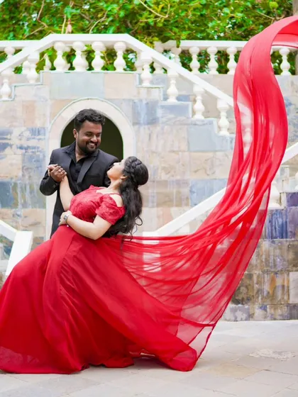A beautiful dance pose with the bride's red gown flowing dramatically. This shot, set against a grand staircase, is full of movement and romance.