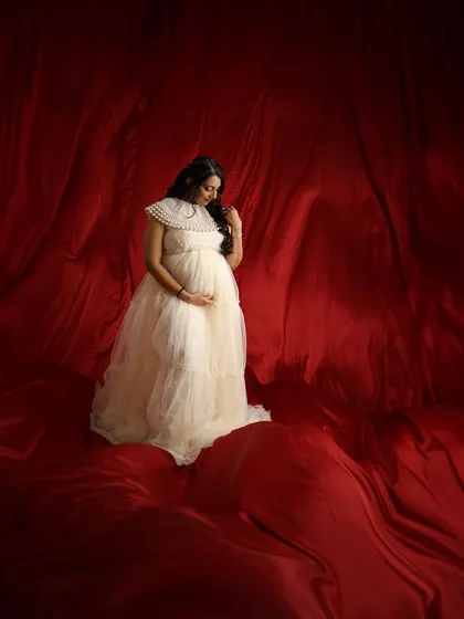 A pensive and beautiful portrait, with the soft cream gown standing out against the deep red fabric.